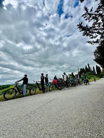 A group of cyclists on a paved road with a cloudy sky above. 2