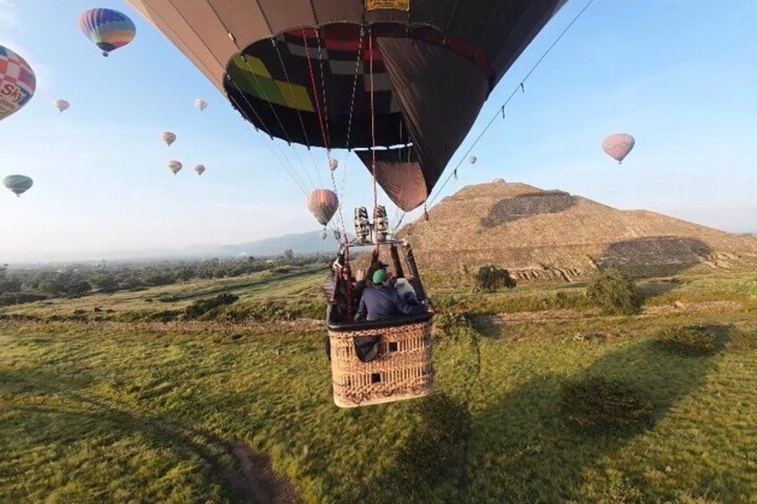 A hot air balloon with passengers, a grassy landscape, and distant mountains. 4