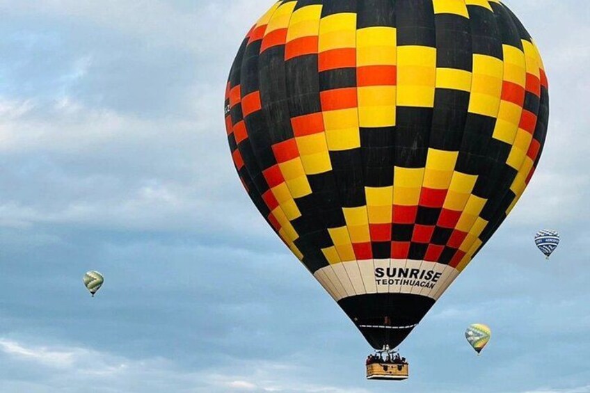 A colorful hot air balloon with 'SUNRISE' written on it, flying in the sky. 2
