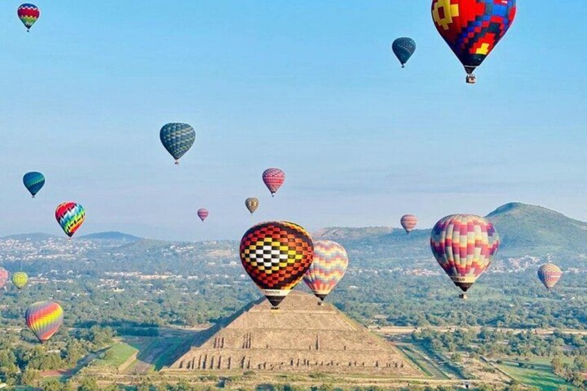 A hot air balloon festival with colorful balloons over a landscape with fields and hills. 5