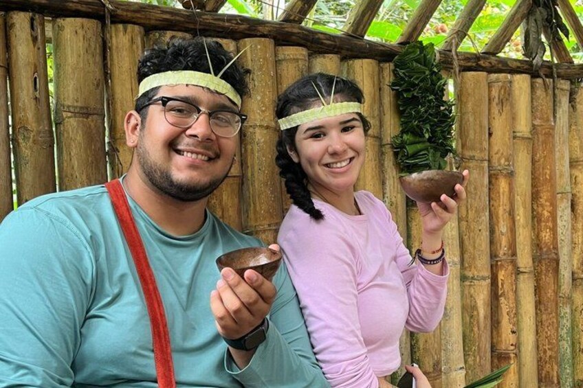 Two people holding bowls, standing in front of a bamboo structure. 2