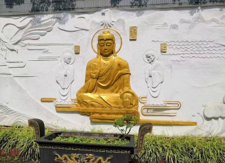 A large golden Buddha statue with intricate carvings on the wall behind it. 2