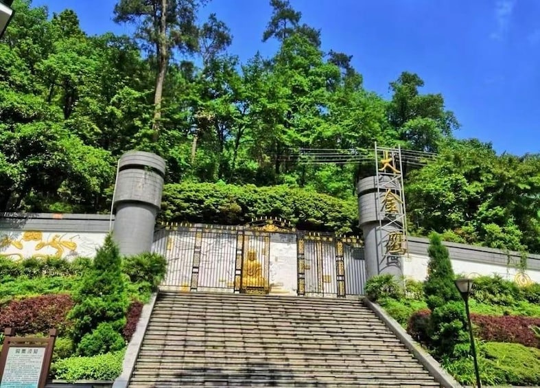 A temple entrance with a golden statue, a gate, and a staircase leading up to it. 1