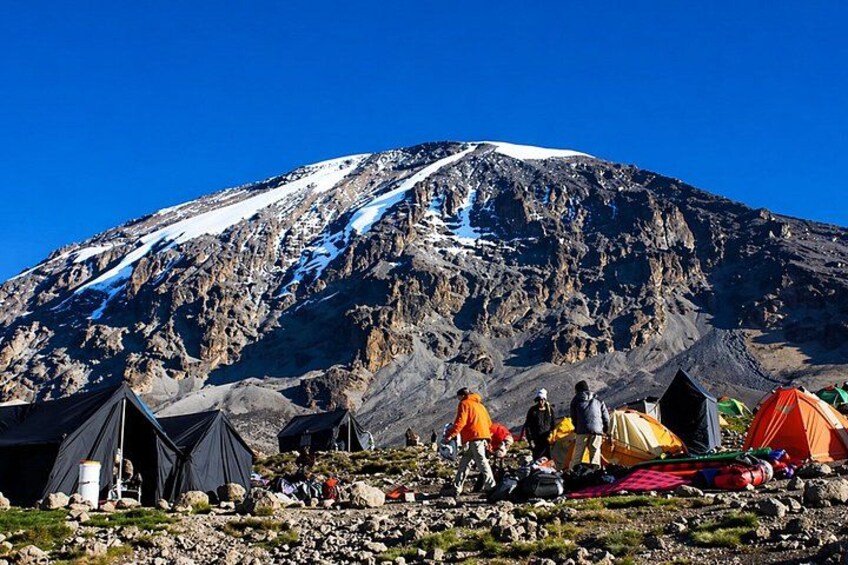 A mountainous landscape with tents and hikers. 2