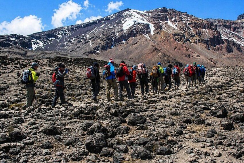 A group of hikers on a rocky terrain with a mountain in the background. 4