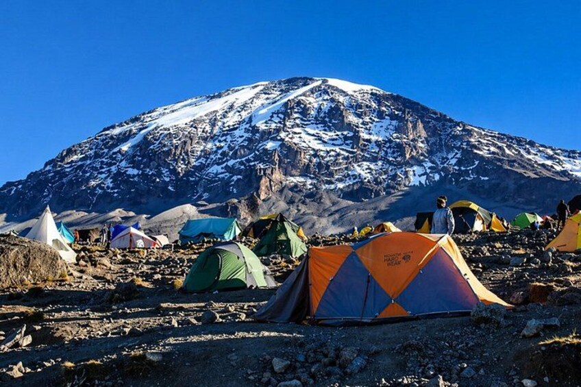 A snowy mountain with tents in a rocky terrain. 3