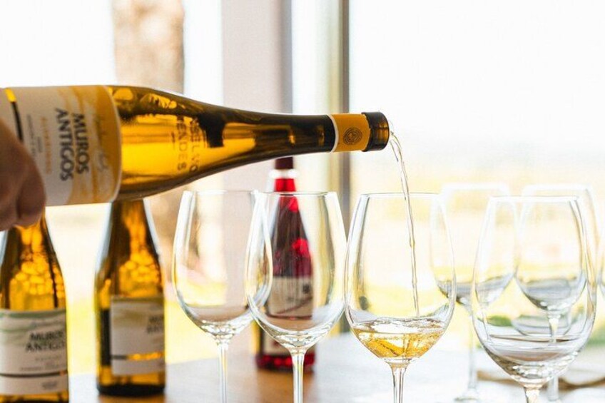 A bottle of wine being poured into glasses. 1