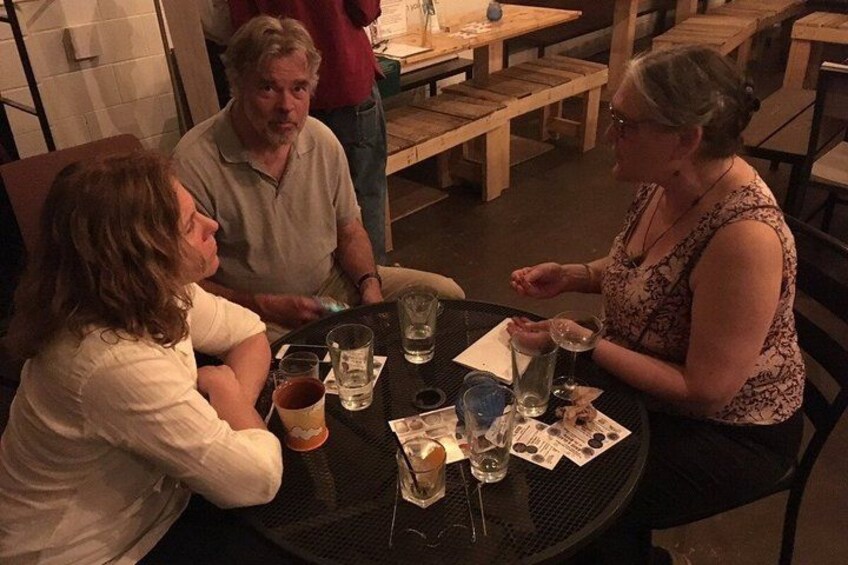 A group of people sitting around a round table with drinks and a menu. 3