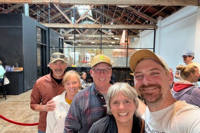 A group of people in an indoor setting with industrial-style architecture, including metal beams and glass windows. 4