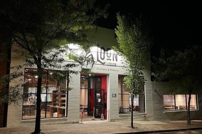 A building with a sign that reads 'LOON Liquor Distillery & Pizzeria' at night. 5