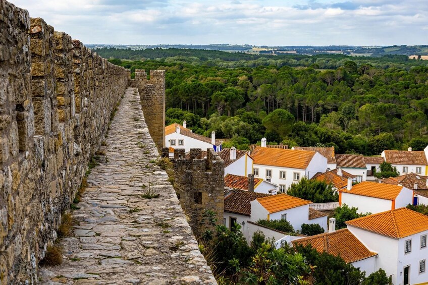 A stone wall, a cobblestone path, and white buildings with orange roofs. 4