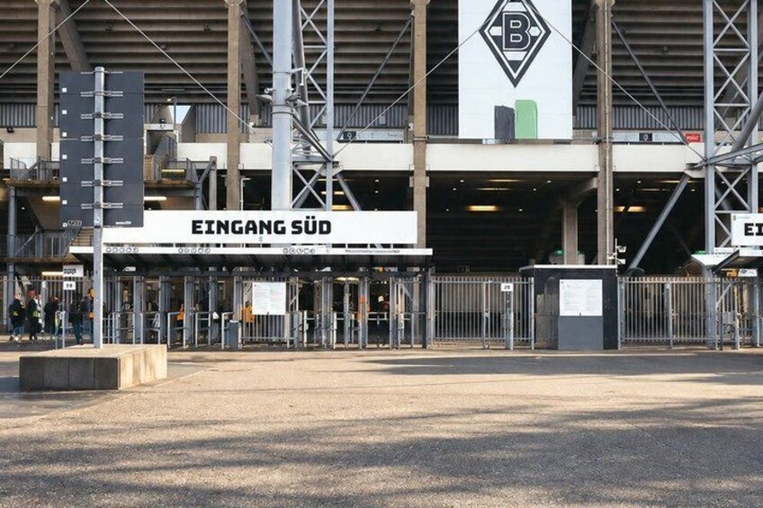 A large industrial building with a sign reading 'EINGANG SÜD' and a logo above the entrance. 3