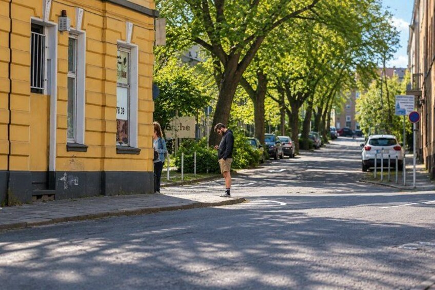 A street with parked cars, a yellow building, and a person walking. 2