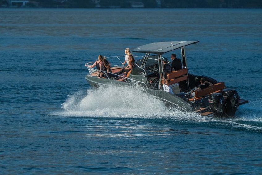 A speedboat with passengers on a calm body of water. 5