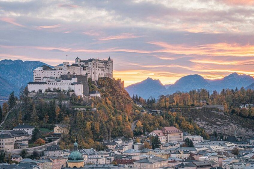 A castle on a hill, a town below, and mountains in the background. 5