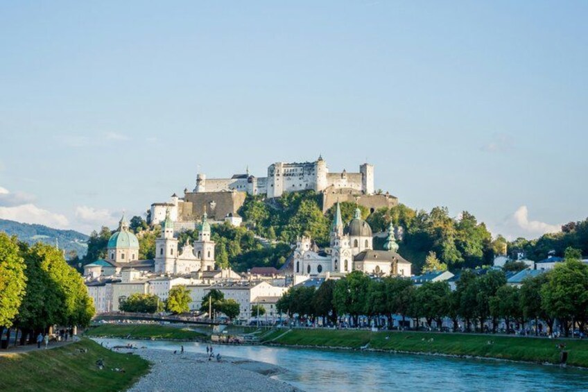 A historic castle on a hill with a river in the foreground. 4