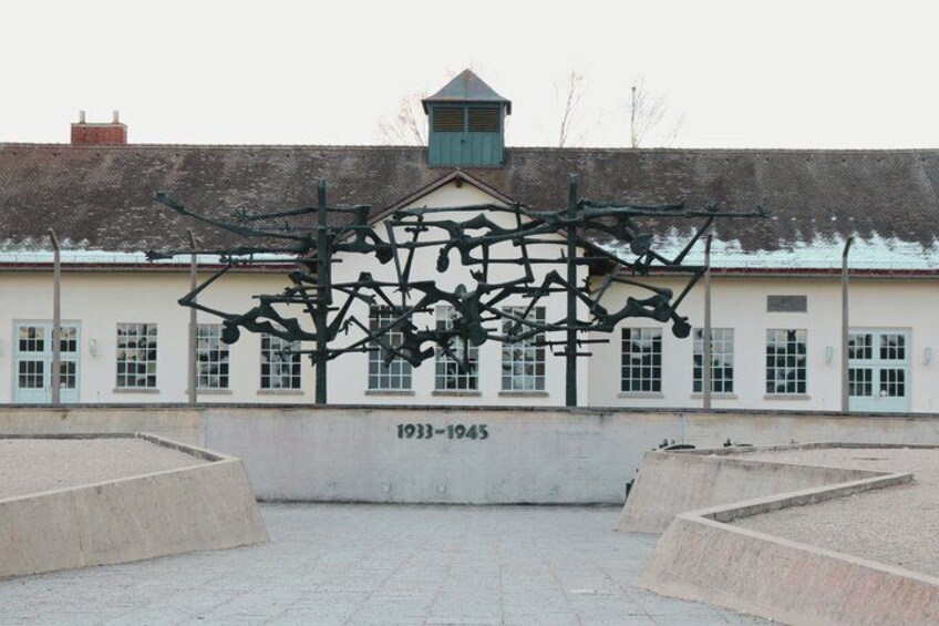 A building with a date plaque reading '1933-1945' and a sculpture in front. 2
