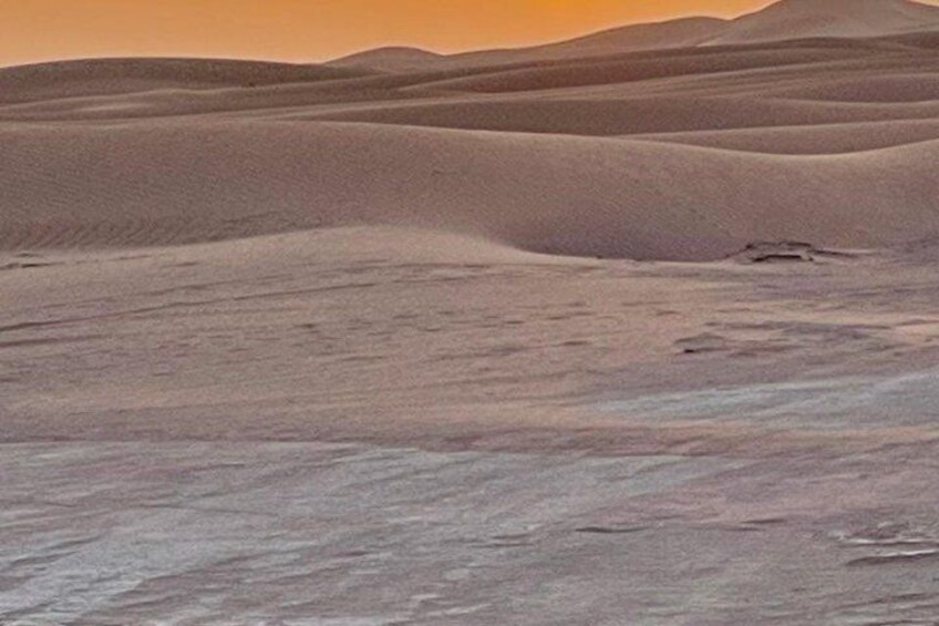 A desert landscape with rolling sand dunes and a clear sky. 5