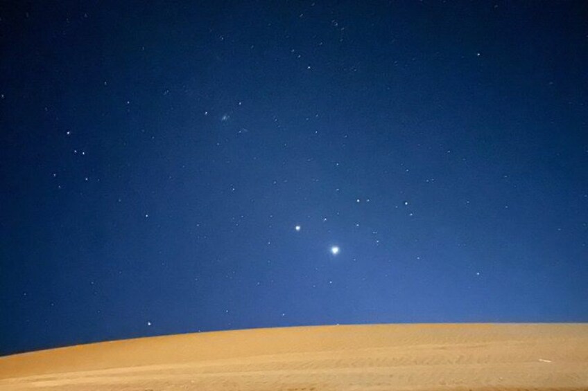 A desert landscape at night with a clear sky and visible stars. 2