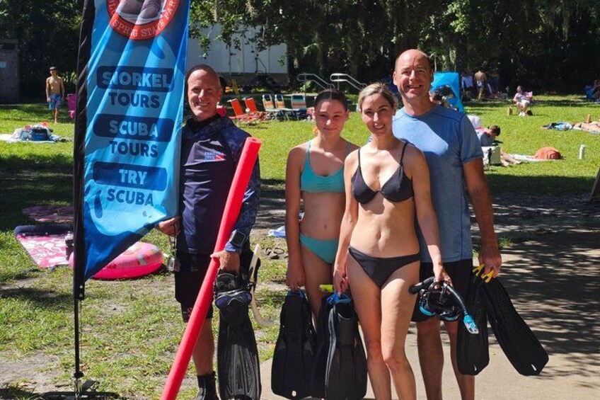 A group of people with scuba diving gear, a flag, and a grassy park. 2
