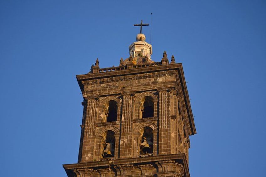 A tall, ornate church tower with a cross on top, detailed stonework, and arched windows. 5