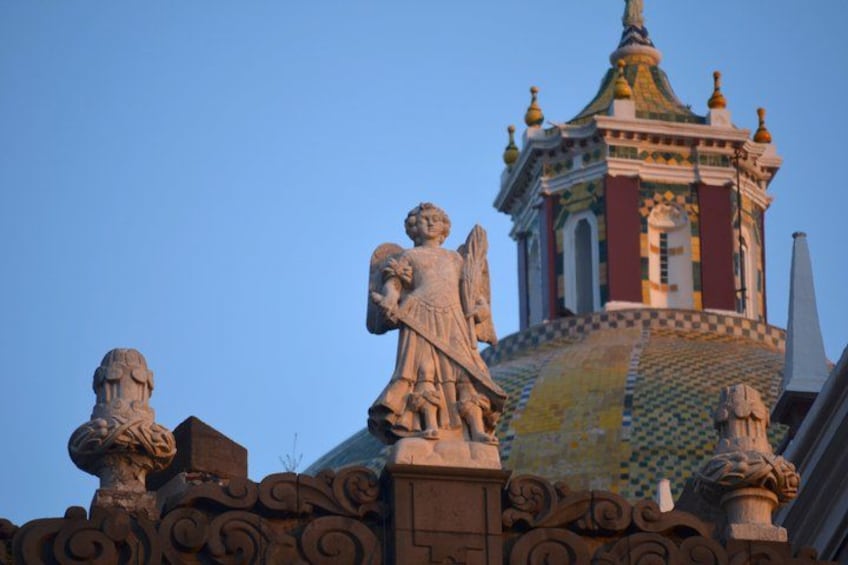 A building with a colorful dome and statues on its roof. 2