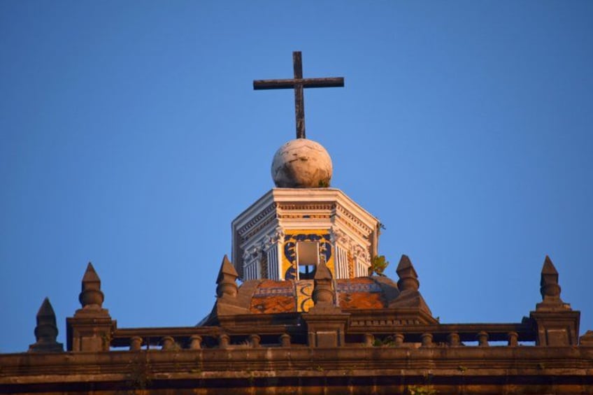 A large, ornate building with a prominent cross on top, detailed architecture, and a clear blue sky. 4