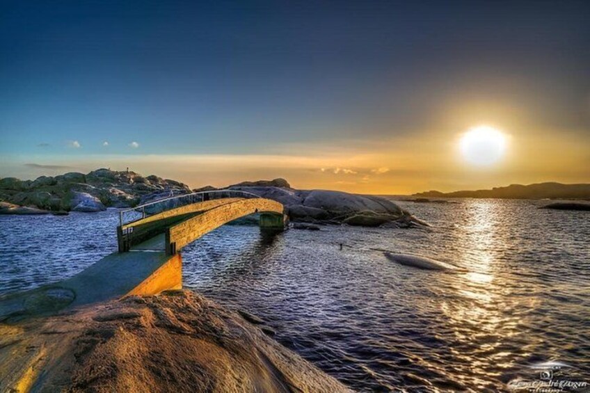 A stone bridge over water, a sunset, and a rocky shoreline. 3
