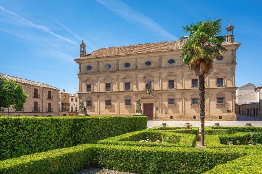 A historic building with a symmetrical facade, a palm tree, and a well-manicured garden. 4