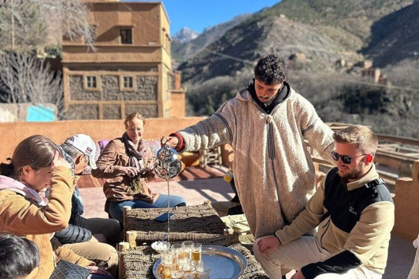 A group of people sitting outdoors, one person pouring a drink into a glass. 2