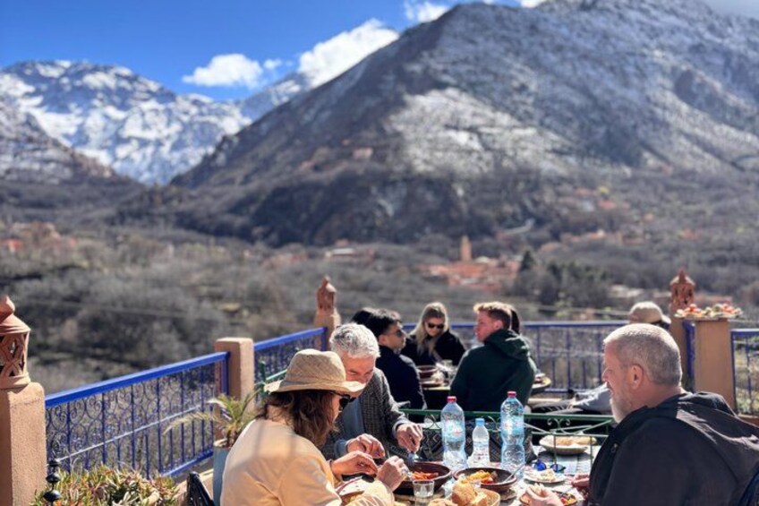 A group of people dining outdoors with a mountainous landscape in the background. 4