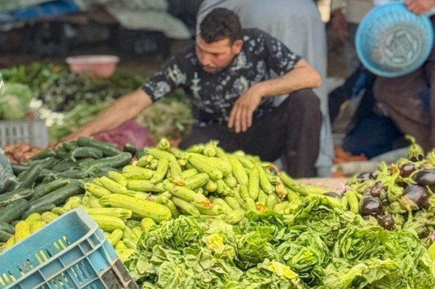 A market stall with various vegetables like cucumbers, eggplants, and leafy greens. 5