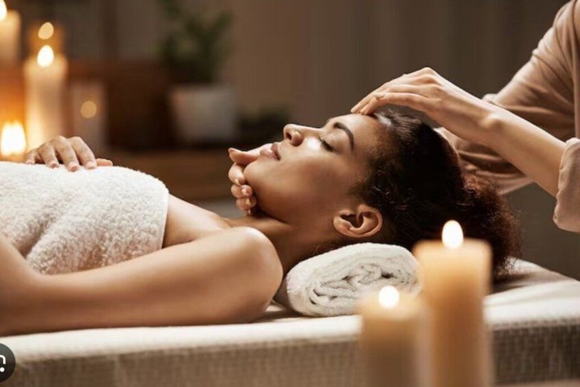 A person receiving a massage with candles in the background. 5