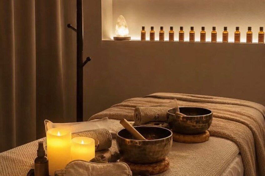 A massage therapy room with candles, bowls, and essential oils. 1