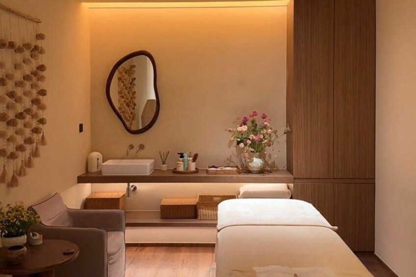 A modern bathroom with a vanity, mirror, and a small seating area. 1