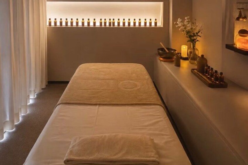 A spa room with a massage table, candles, and essential oils. 4