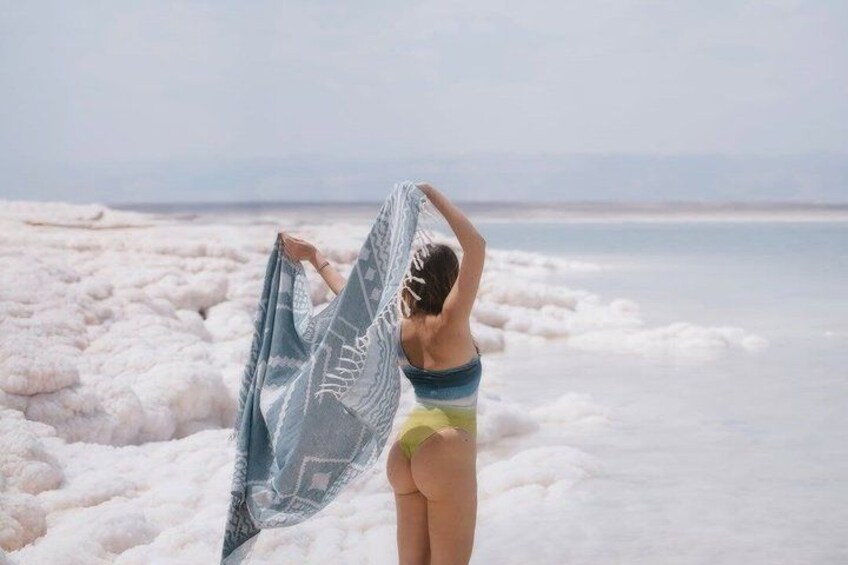 A person standing on a salt flat with a body of water in the background. 5