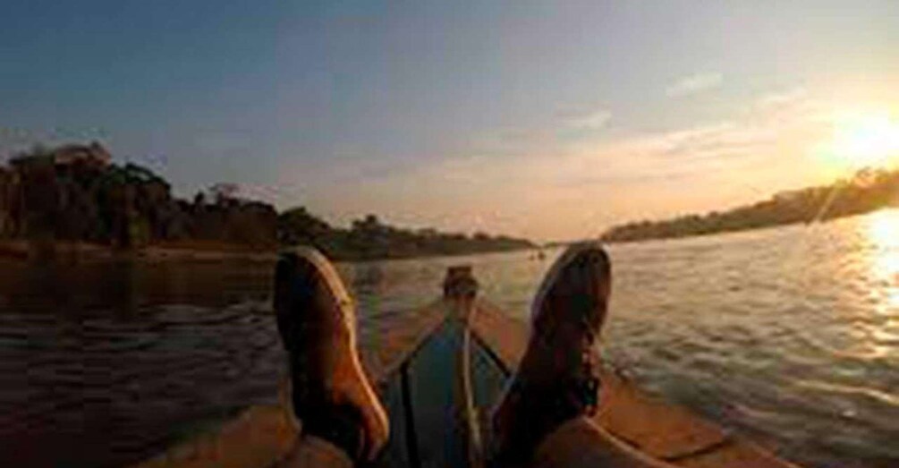 Ein Boot auf einem Fluss, im Hintergrund ein Sonnenuntergang. 3