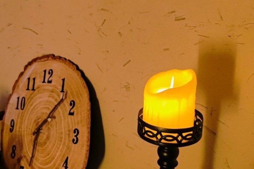 A wooden clock and a lit candle on a wall. 3