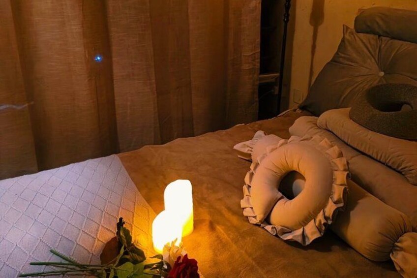 A bed with pillows, a glowing bedside lamp, and a bouquet of flowers. 5