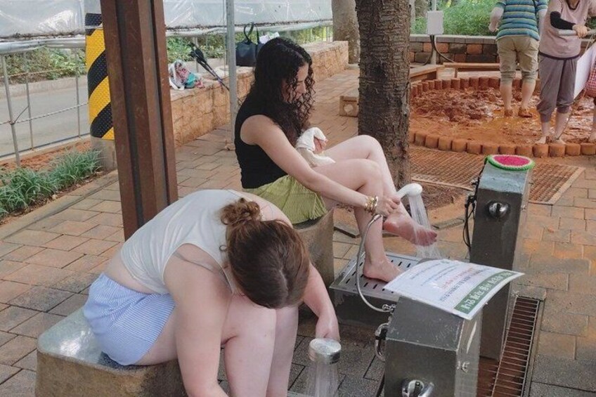 A woman sitting on a bench, a water fountain, and a tree in a park. 5