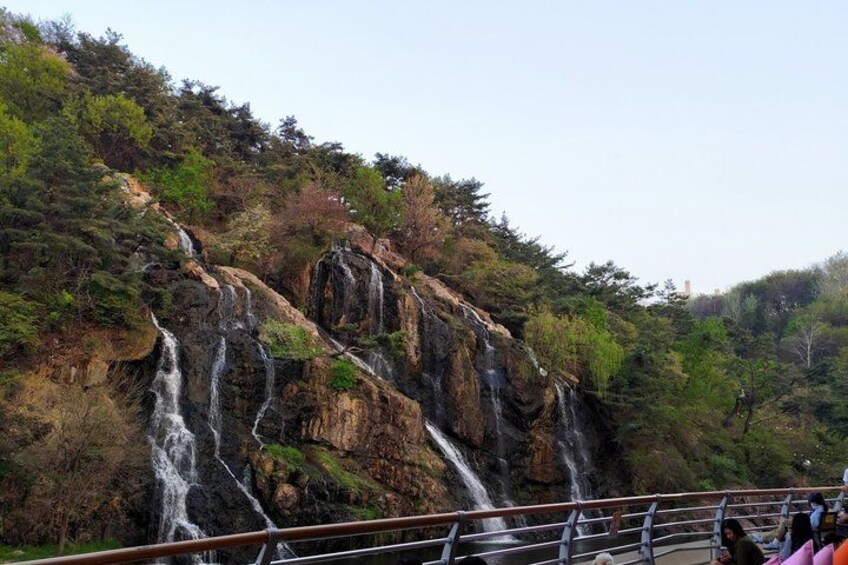 A waterfall cascading down a rocky cliff surrounded by dense forest. 3