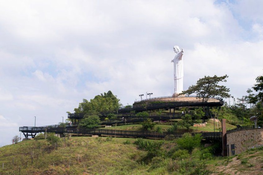 A large white statue on a hill with a viewing platform and a bridge. 4