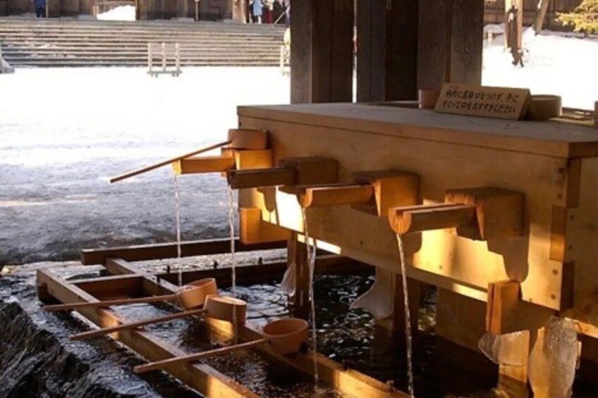 A wooden water pump with multiple spouts and containers. 5