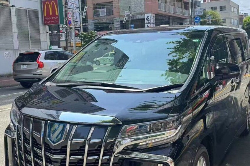 A black SUV parked on a street with buildings and a McDonald's sign in the background. 3