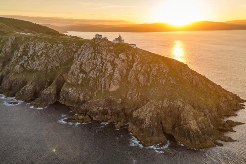 A coastal landscape with a rocky cliff and a lighthouse at sunset. 3