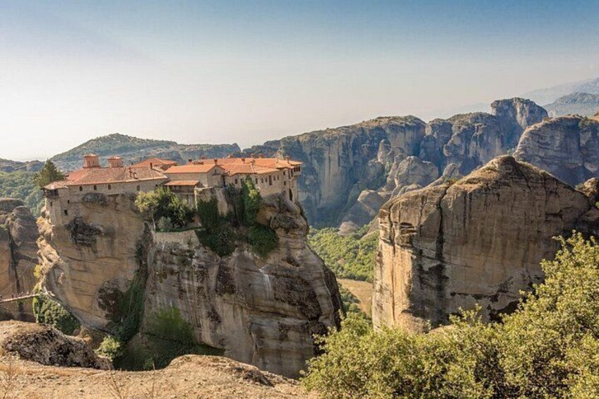 A monastery perched on a cliff, surrounded by rocky terrain and greenery. 4