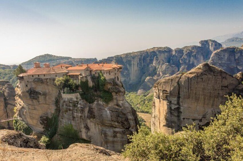 A monastery perched on a cliff, surrounded by rocky terrain and greenery. 4