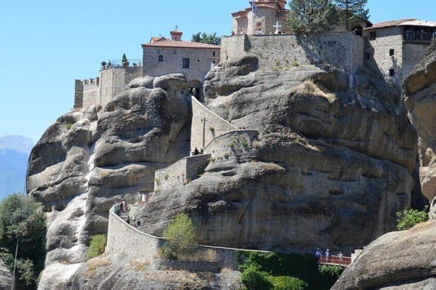 A monastery built on a rocky cliff with a staircase leading up to it. 2