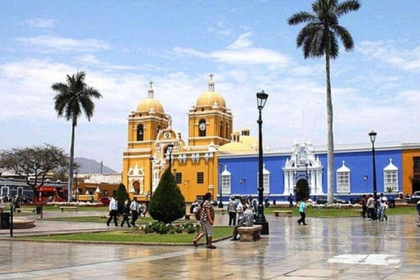 A plaza with a yellow building, palm trees, and a blue building in the background. 4